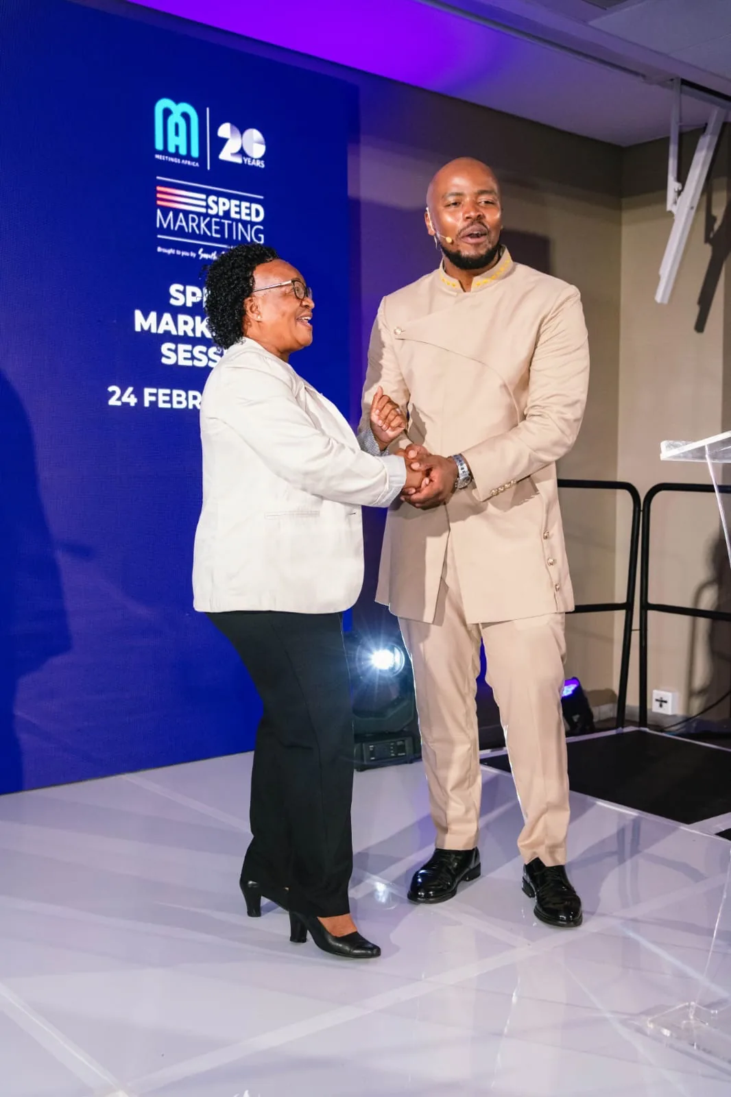 Host welcoming a speaker on stage in front of the Meetings Africa 20 Years LED wall