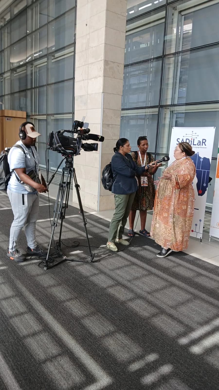 Broadcast crew filming a media interview in the CTICC foyer during the National Language Summit