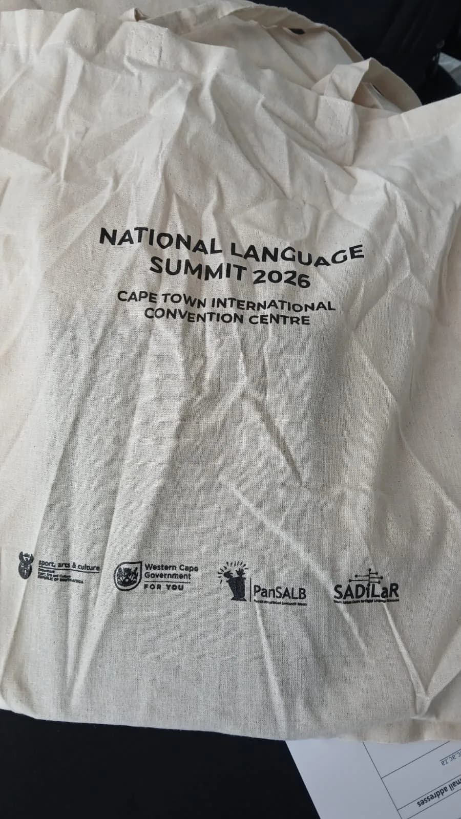 Branded National Language Summit delegate tote bag carrying the department and partner logos